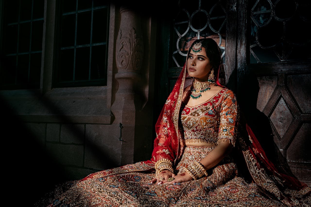 who-we-are Elegant South Asian bride wearing a red and gold embroidered lehenga.