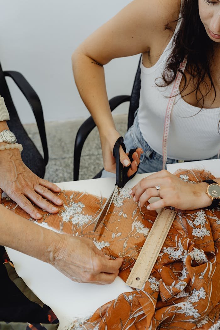 Mastering the First Impression: Your intriguing post title goes here A woman cutting floral fabric with scissors, illustrating the art of tailoring in a sewing workshop.
